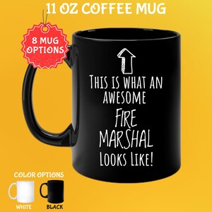 May include: Black 11 oz coffee mug with the text "THIS IS WHAT AN AWESOME FIRE MARSHAL LOOKS LIKE!" in white. The mug has a black handle and the words "8 MUG OPTIONS" are visible. Color options are white and black.