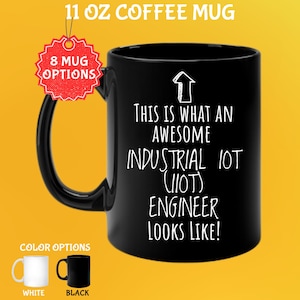 Op de afbeelding: Zwarte koffiemok van 325 ml met de tekst "THIS IS WHAT AN AWESOME INDUSTRIAL IOT (IIOT) ENGINEER LOOKS LIKE!". De mok heeft een zwart oor en wordt getoond met witte en zwarte kleuropties.