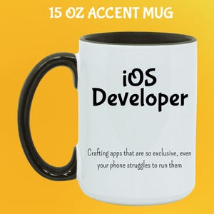 May include: White 444 ml accent mug with a black handle and rim. The mug features the text "iOS Developer" in black, along with a humorous quote about app development. The mug is designed for coffee or tea.