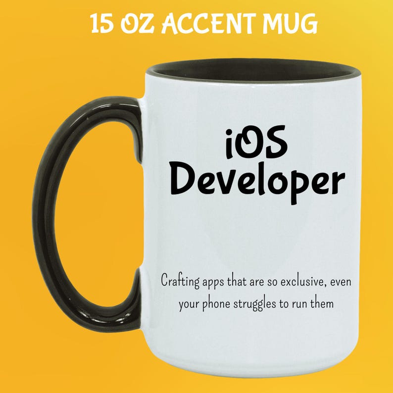 May include: White 444 ml accent mug with a black handle and rim. The mug features the text "iOS Developer" in black, along with a humorous quote about app development. The mug is designed for coffee or tea.