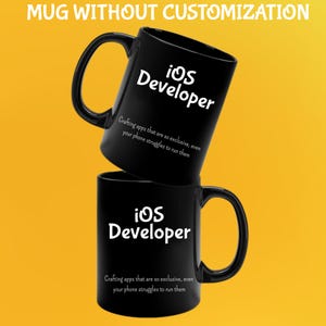 May include: Two black ceramic mugs, each with a large handle. The mugs display the text "iOS Developer" in white, with the phrase "Crafting apps that are so exclusive, even your phone struggles to run them" below it.