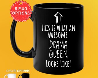 Op de afbeelding: Zwarte koffiemok van 325 ml met de witte tekst "THIS IS WHAT AN AWESOME DRAMA QUEEN LOOKS LIKE!". De mok heeft een zwart handvat en de afbeelding bevat kleuropties: wit en zwart. De afbeelding bevat ook de tekst "8 MUG OPTIONS".