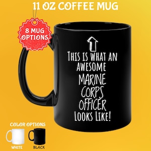 Puede incluir: Taza de café negra de 325 ml con el texto blanco "THIS IS WHAT AN AWESOME MARINE CORPS OFFICER LOOKS LIKE!". La taza tiene un asa negra y se muestra con opciones de color blanco y negro.