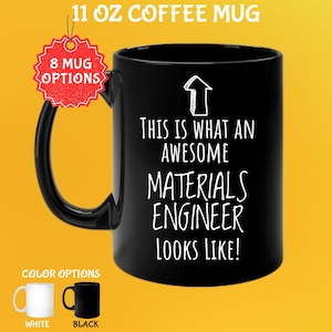 以下が含まれることがあります： 「THIS IS WHAT AN AWESOME MATERIALS ENGINEER LOOKS LIKE!」の白い文字が入った黒い325mlコーヒーマグ。マグには黒いハンドルがあり、画像には白と黒のカラーオプションが表示されています。マグには「8 MUG OPTIONS」と書かれたタグが付いています。