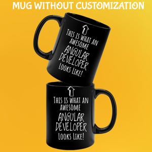 May include: Two black coffee mugs stacked on top of each other. The mugs have a curved handle and the text "THIS IS WHAT AN AWESOME ANGULAR DEVELOPER LOOKS LIKE!" in white. The background is yellow.