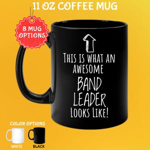 May include: Black 11 oz coffee mug with the text "THIS IS WHAT AN AWESOME BAND LEADER LOOKS LIKE!" in white. The mug has a black handle and a white arrow graphic. Color options include white and black mugs.