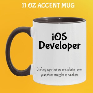 May include: White 11 oz accent mug with a black handle and rim. The mug features the text "iOS Developer" in black, along with a humorous quote about app development. The mug is designed for coffee or tea.