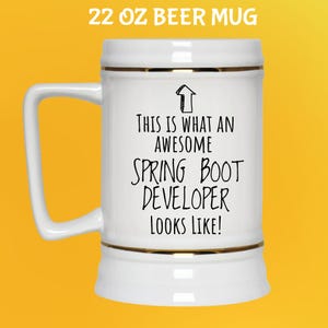 May include: White 650 ml beer mug with gold trim and a handle. The mug has the text "THIS IS WHAT AN AWESOME SPRING BOOT DEVELOPER LOOKS LIKE!" in black. The text is centered on the mug.