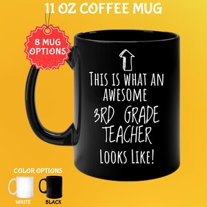 Puede incluir: Taza de café negra de 312g con el texto "THIS IS WHAT AN AWESOME 3RD GRADE TEACHER LOOKS LIKE!" en blanco. La taza tiene un asa negra y las palabras "8 MUG OPTIONS" en una etiqueta roja. Las opciones de color son blanco y negro.