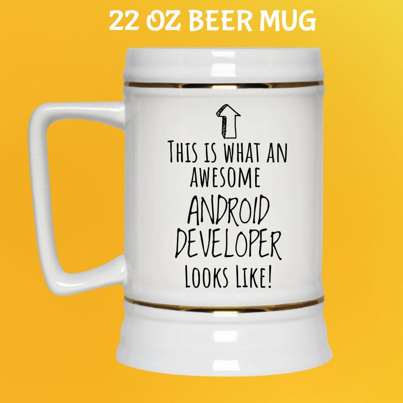K&ouml;nnte beinhalten: Wei&szlig;er 650 ml Bierkrug mit goldenem Rand und Henkel. Der Krug tr&auml;gt den schwarzen Text "THIS IS WHAT AN AWESOME ANDROID DEVELOPER LOOKS LIKE!". Der Krug steht vor gelbem Hintergrund.