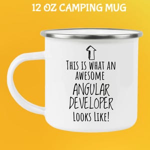 May include: White 12 oz camping mug with a silver rim and handle. The mug features the text "THIS IS WHAT AN AWESOME ANGULAR DEVELOPER LOOKS LIKE!" in black, with an arrow graphic.