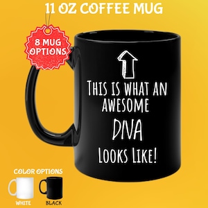 May include: Black 11 oz coffee mug with the text "THIS IS WHAT AN AWESOME DIVA LOOKS LIKE!" in white. The mug has a black handle and is shown with white and black color options. The image also shows "8 MUG OPTIONS".