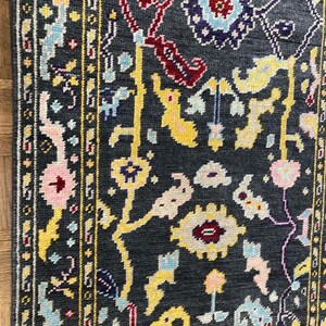 May include: A dark blue rug with a floral pattern in shades of yellow, pink, red, and blue. The rug has a border with a geometric design.
