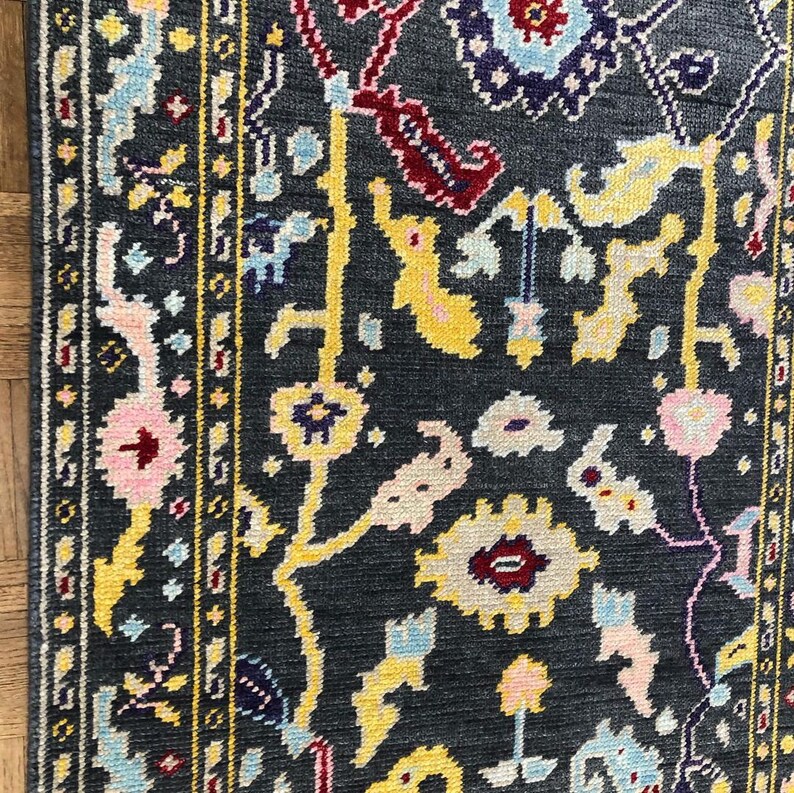 May include: A dark blue rug with a floral pattern in shades of yellow, pink, red, and blue. The rug has a border with a geometric design.