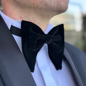 Könnte beinhalten: Eine schwarze Samt-Fliege, die zu einem weißen Hemd und einem schwarzen Smoking getragen wird.