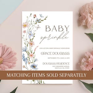 May include: Baby sprinkle invitation with floral accents in pink and blue. The invitation includes the text "Baby Sprinkle", the honoree's name, date, time, and address. The words "Matching items sold separately" are also visible.