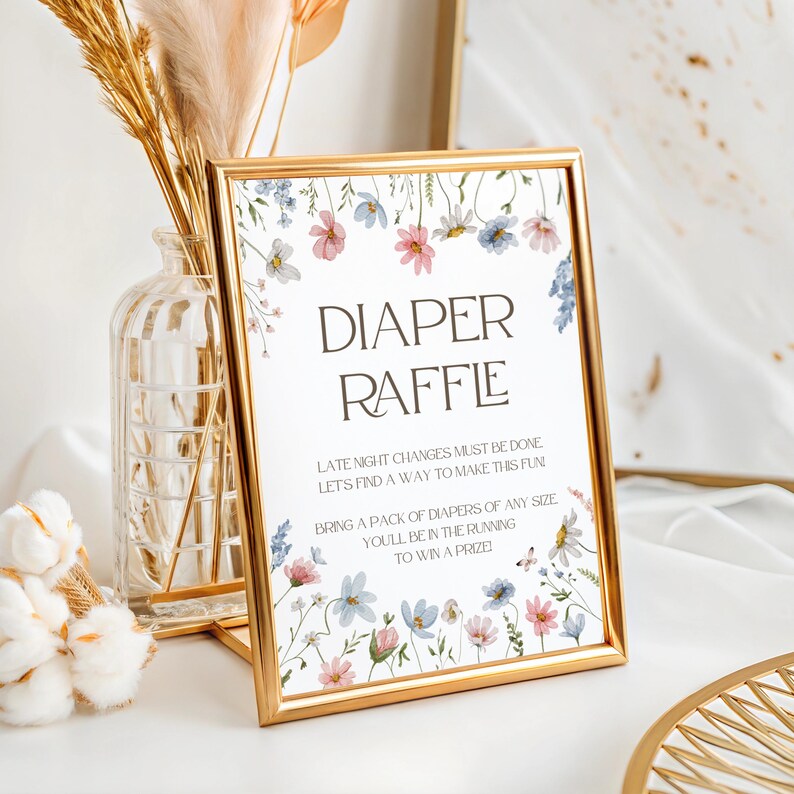 May include: A gold framed sign with a floral design and the text "DIAPER RAFFLE" in brown text. The sign reads "Late night changes must be done, let's find a way to make this fun. Bring a pack of diapers of any size, you'll be in the running to win a prize."