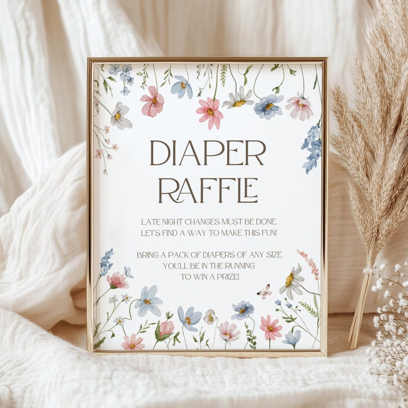 May include: A white sign with a floral border and the text "DIAPER RAFFLE" in brown. The sign also includes the text "Late night changes must be done. Let's find a way to make this fun. Bring a pack of diapers of any size. You'll be in the running to win a prize!"