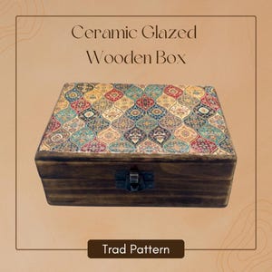 Puede incluir: Caja de madera vidriada de cerámica con base de madera marrón oscuro y tapa estampada colorida. La tapa presenta un diseño tradicional en tonos rojos, azules, amarillos y verdes. La caja tiene un cierre metálico. El texto "Ceramic Glazed Wooden Box" y "Trad Pattern" son visibles.