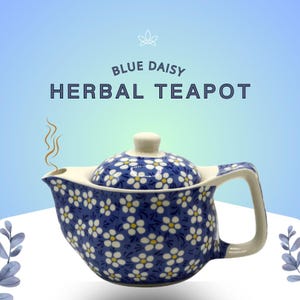 May include: A blue and white ceramic teapot with a floral daisy pattern. The teapot has a lid, handle, and spout. The text "BLUE DAISY HERBAL TEAPOT" is displayed above the teapot. Steam rises from the spout.