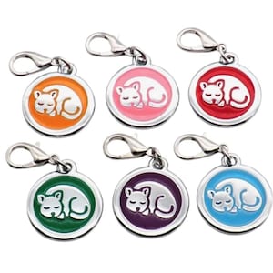 May include: Six colorful cat charm keychains with a silver metal ring. The charms are round and feature a white silhouette of a sleeping cat on a colored background. The colors are orange, pink, red, green, purple, and blue.
