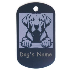 May include: A black dog tag with a silver illustration of a Labrador Retriever. The tag has a hole at the top for attachment and the words "Dog's Name" are printed at the bottom.
