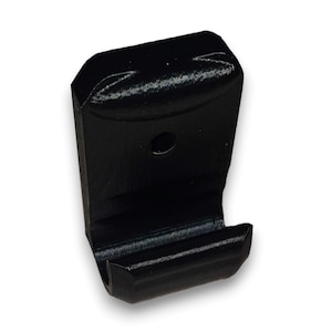 Peut inclure: Crochet mural en plastique noir avec un sommet arrondi et un seul crochet qui s'étend vers le bas. Le crochet a un petit trou en haut pour l'accrocher.