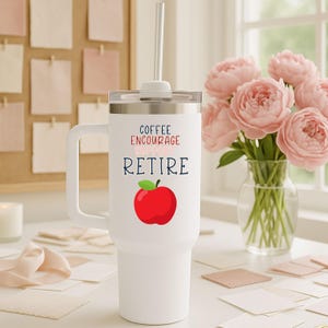 May include: White insulated tumbler with a handle and a straw. The tumbler features the words "Coffee Encourage Support Retire" in black and red, with a red apple graphic. The tumbler is designed for hot or cold beverages.