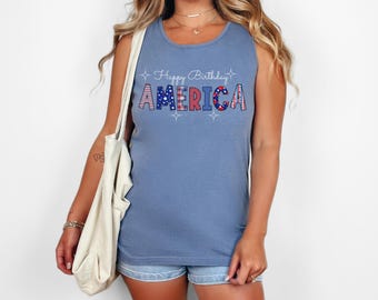 May include: A blue sleeveless tank top with the text "Happy Birthday America" in white with red, white, and blue stars and stripes patterned letters.