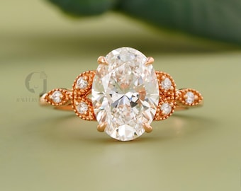 May include: Rose gold engagement ring featuring an oval-cut diamond center stone. The ring has a detailed band with smaller accent diamonds. The setting is a classic, elegant design, perfect for a proposal or special occasion.