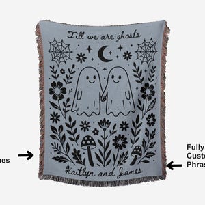 May include: A light blue woven throw blanket with a black and white ghost design. The blanket features the text "Till we are ghosts" and the names "Kaitlyn and James". The design includes ghosts, flowers, and a spiderweb.