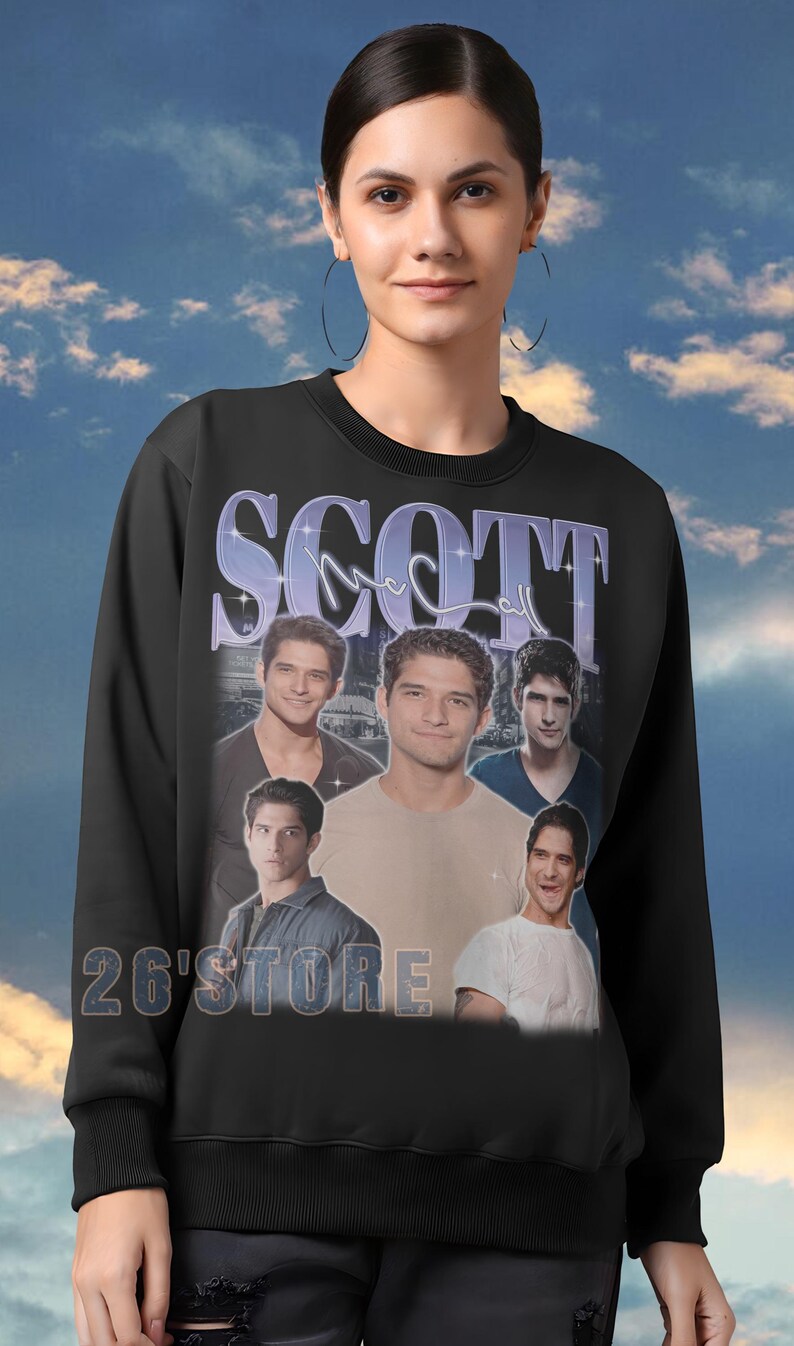 K&ouml;nnte beinhalten: Schwarzes Sweatshirt mit dem Namen "SCOTT" in einer violetten, stilisierten Schriftart. Das Sweatshirt zeigt mehrere Bilder einer Person. Der Text "26'STORE" ist unten aufgedruckt. Der Hintergrund ist ein blauer Himmel mit Wolken.