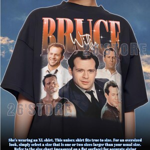 May include: Black unisex t-shirt featuring a collage of Bruce Willis images with the name "Bruce Willis" in orange and white text. The shirt includes the text "26'STORE" and a sizing guide.