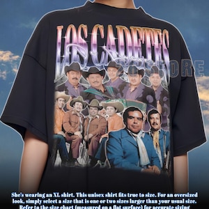 Op de afbeelding: Zwart unisex T-shirt met een groep mannen in hoeden en pakken, met de tekst "LOS CADETES" in een verloop. Het shirt heeft korte mouwen en een ronde hals. Het ontwerp is in vintage stijl.