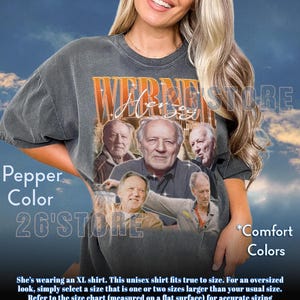 May include: Pepper-colored unisex t-shirt featuring a collage of images and the name "Werner Herzog" in an orange and white design. The shirt also has the text "26'STORE" and "Comfort Colors".