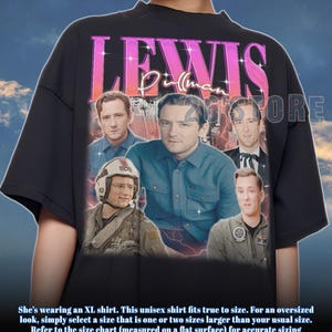 Puede incluir: Camiseta unisex negra con un gráfico de Lewis Pullman y el texto "LEWIS Pullman" en rosa y morado. La camiseta tiene cuello redondo y mangas cortas. La camiseta también tiene el texto "201STORE".