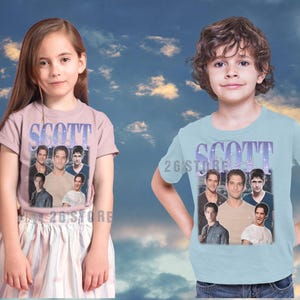 K&ouml;nnte beinhalten: Zwei Kinder tragen T-Shirts mit einem grafischen Design. Die Shirts zeigen das Wort "SCOTT" in einer stilisierten Schriftart, zusammen mit einer Collage von Bildern. Die T-Shirts sind hellrosa und hellblau.