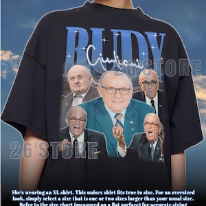 Könnte beinhalten: Schwarzes Unisex-T-Shirt mit einer Collage von Bildern eines Mannes, mit dem Namen "RUDY" in blauen Blockbuchstaben über den Bildern. Das Shirt hat auch den Text "Giuliani" in Kursivschrift und den Shop-Namen "26'STORE".