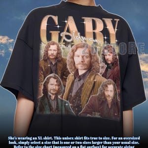 Puede incluir: Camiseta unisex negra con un collage de imágenes de Gary Oldman. La camiseta tiene el nombre "GARY" en una fuente dorada y brillante. El texto "26STORE" también es visible. La camiseta es talla XL.