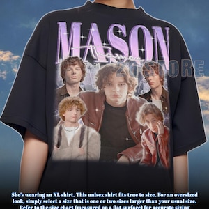 May include: Black unisex t-shirt featuring a collage of images of a person, with the name "MASON" in a purple, stylized font. The shirt includes the text "STORE" in white. The shirt is an XL size.