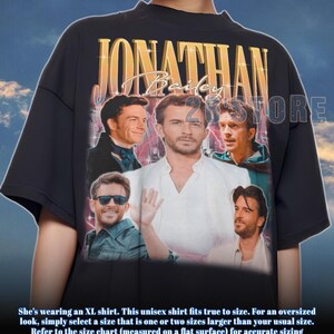 May include: Black unisex t-shirt featuring a collage of images of Jonathan Bailey, with the name "Jonathan Bailey" in gold lettering. The shirt has a vintage, distressed look.