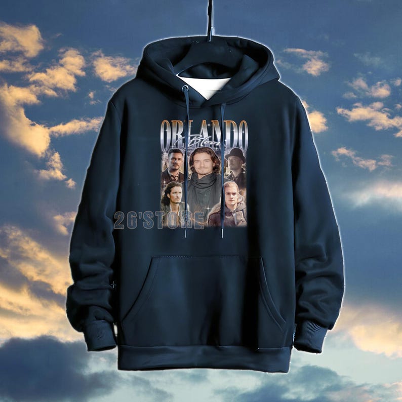 May include: Navy blue hooded sweatshirt featuring a graphic of Orlando Bloom and the text "ORLANDO Bloom". The sweatshirt has a front pocket and a drawstring hood. The text "26'Store" is printed at the bottom.