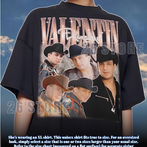 May include: Black unisex t-shirt featuring a graphic of a group of men wearing cowboy hats. The shirt has the text "VALENTIN Elizalde" in a rose gold font. The store name "26'STORE" is also visible on the shirt.
