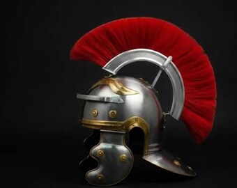 May include: A polished silver Roman helmet with gold accents and a vibrant red plume. The helmet features a brow guard, cheek pieces, and decorative rivets. This historical replica is a striking piece of armor.