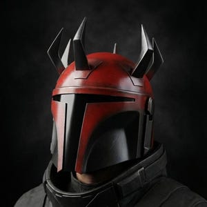 May include: A red and black helmet with angular horns, reminiscent of a Mandalorian design. The helmet features a T-shaped visor and is worn with a black jacket, creating a striking, futuristic look.