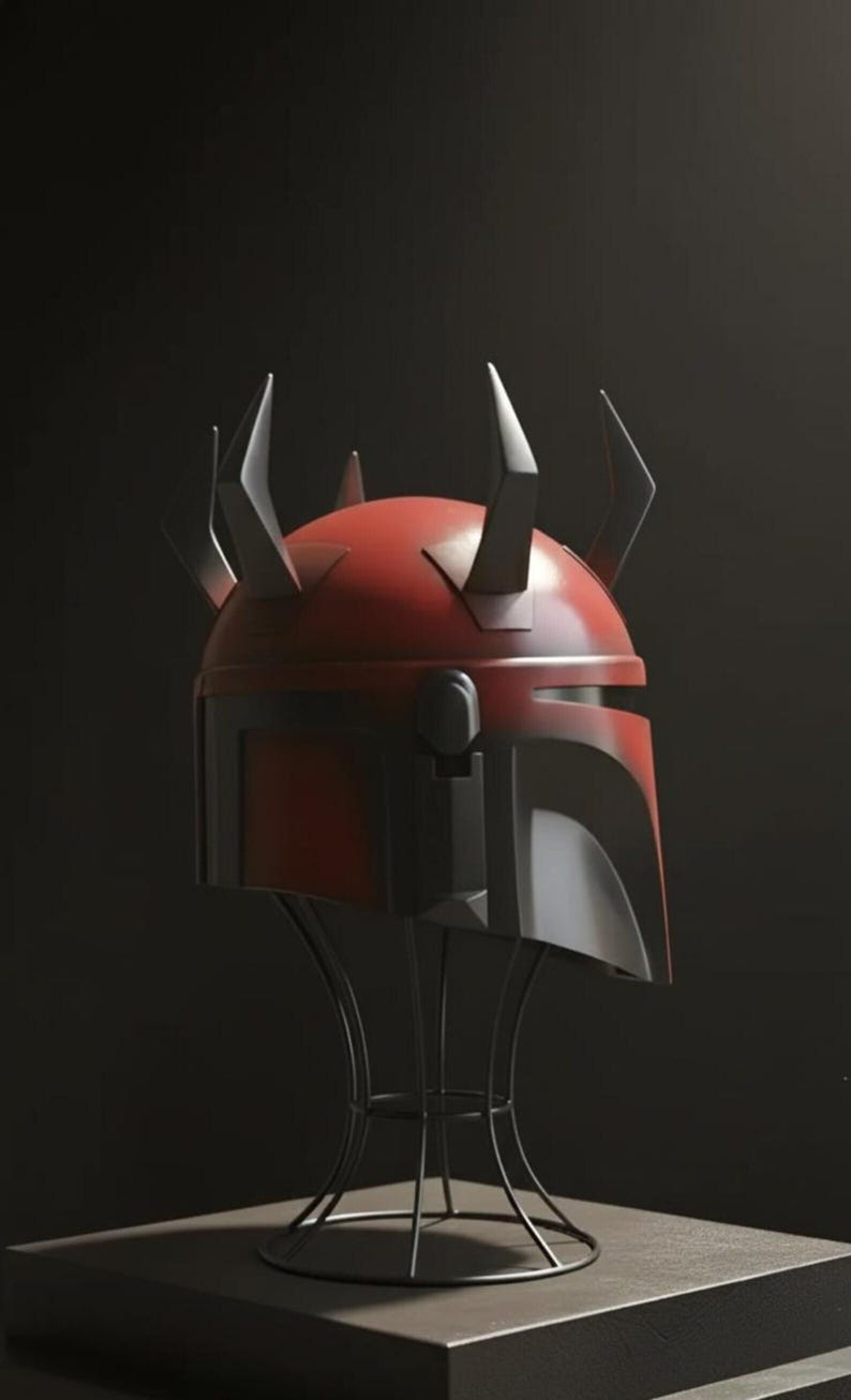 May include: A red and black helmet with multiple horns, displayed on a black metal stand. The helmet has a glossy finish and a distinctive design, likely for cosplay or display. The background is a dark, solid colour.