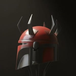 May include: A red and black helmet with pointed horns, displayed on a wire stand. The helmet has a distinctive design with a visor and angular features. The horns are black and add a unique element to the overall aesthetic.