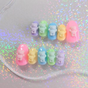 Puede incluir: Un conjunto de diez puntas de uñas de color pastel con un diseño de oso en 3D. Los osos son de varios colores pastel, incluyendo rosa, azul, verde y amarillo.