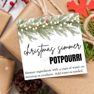 Może przedstawiać: Etykieta prezentu o tematyce świątecznej z czarnym napisem "christmas simmer POTPOURRI". Etykieta ozdobiona jest girlandą światełek i gałązkami iglastymi. Dołączono instrukcje dotyczące gotowania potpourri.