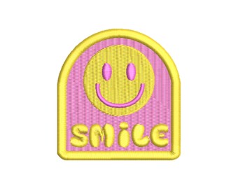 May include: A pink and yellow embroidered patch with a smiley face and the word "SMILE" in yellow letters.